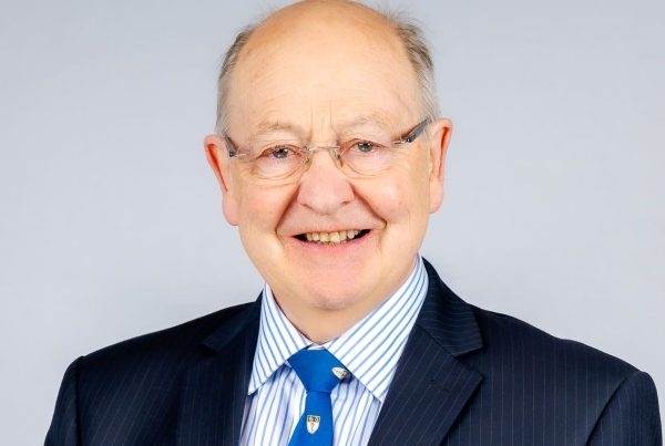 Bevan Commissioner Professor Ewan Macdonald wearing a dark suit and blue tie.
