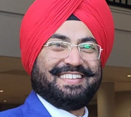 Bevan Fellow Inderpal Singh wearing a blue suit, red tie and red turban