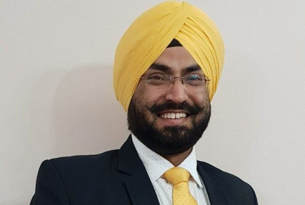Dr Inderpal Singh yn gwisgo siwt ddu